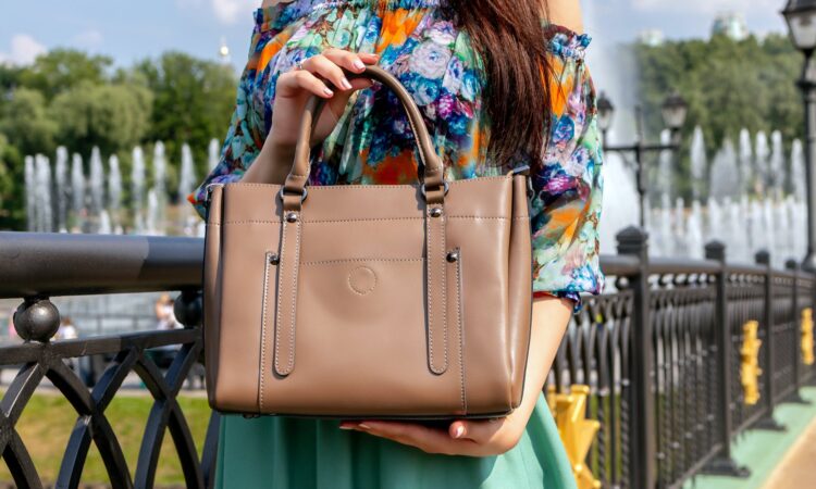 photo of person holding brown leather handbag