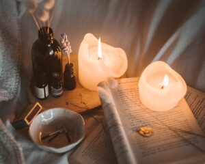lighted candle on white book beside black glass bottle